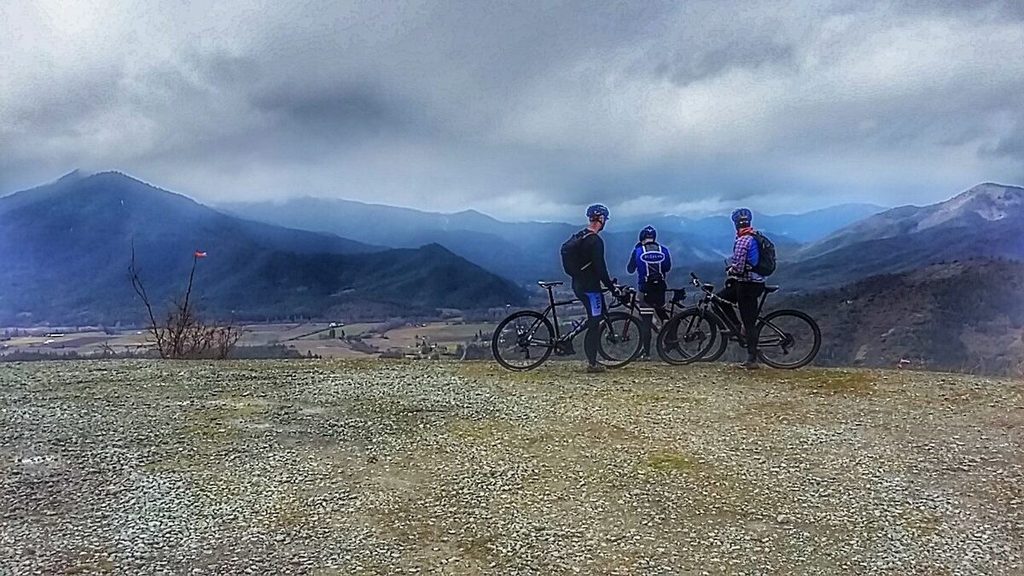 Three riders with their bikes look out over the Applegate Valley from Woodrat Mountain.