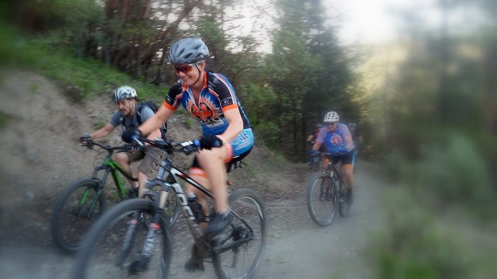Three mountain bikers riding together on a dirt trail.